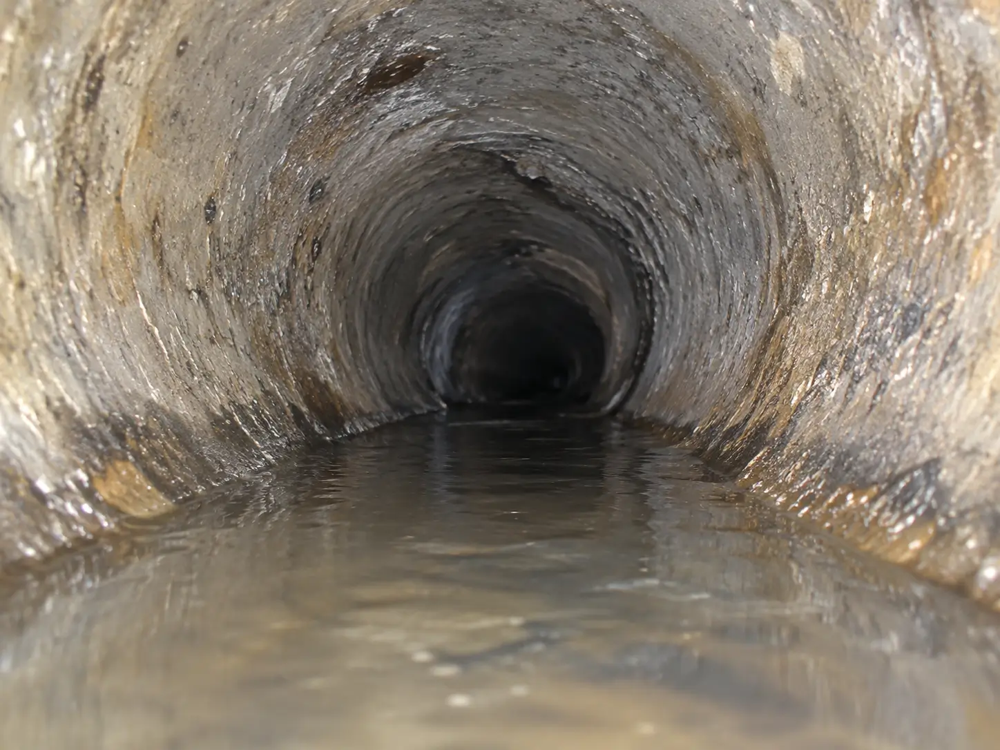 Sewer camera view down a pipe with water pooled along the bottom of the pipe