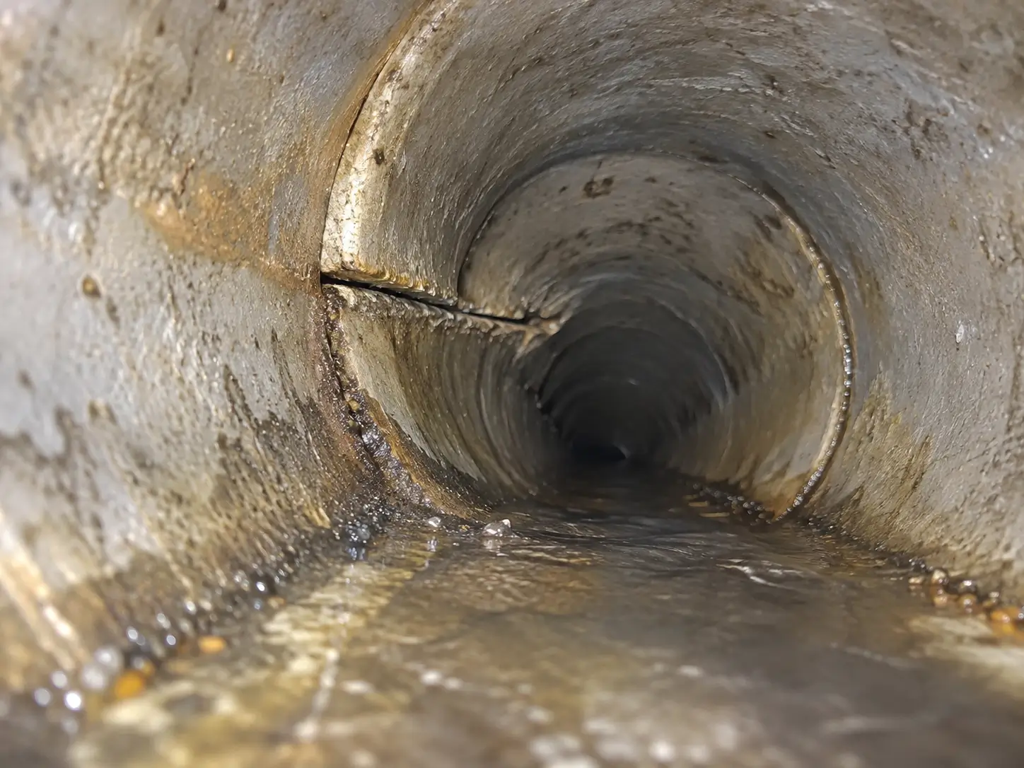 Sewer camera view along a pipe showing a seam where two sections meet, with the pipe edges not lining up