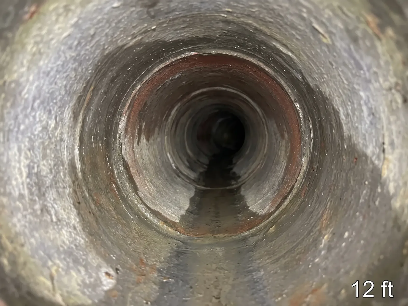 The inside of a sewer pipe seen by a camera, with a 12 ft distance counter in the corner